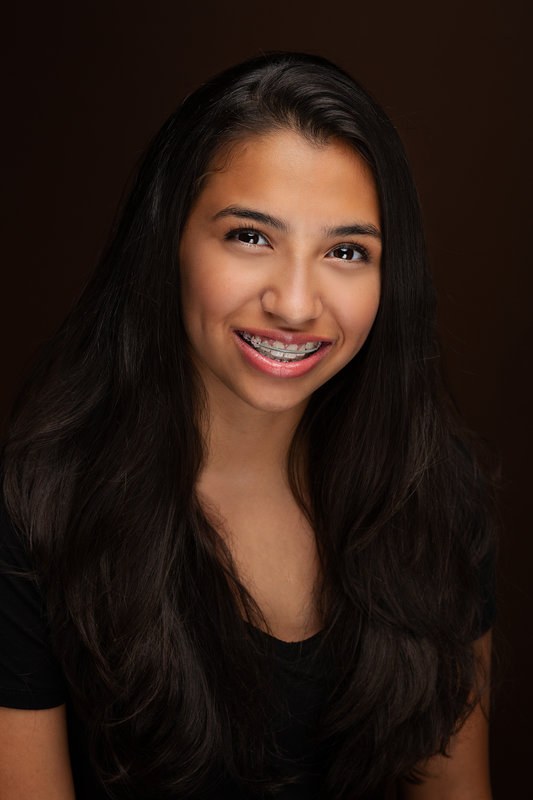 Teen girl smiling on a dark backdrop